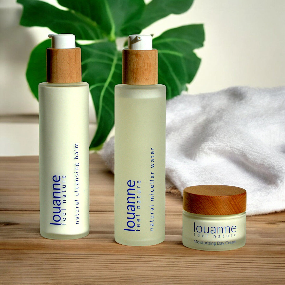 Drei vegane Naturkosmetikprodukte von Esprit Naturel – Anti-Aging , Mizellenwasser und Cleansing Balm mit allergenfreiem Duft, dekorativ arrangiert mit Blättern und Handtuch