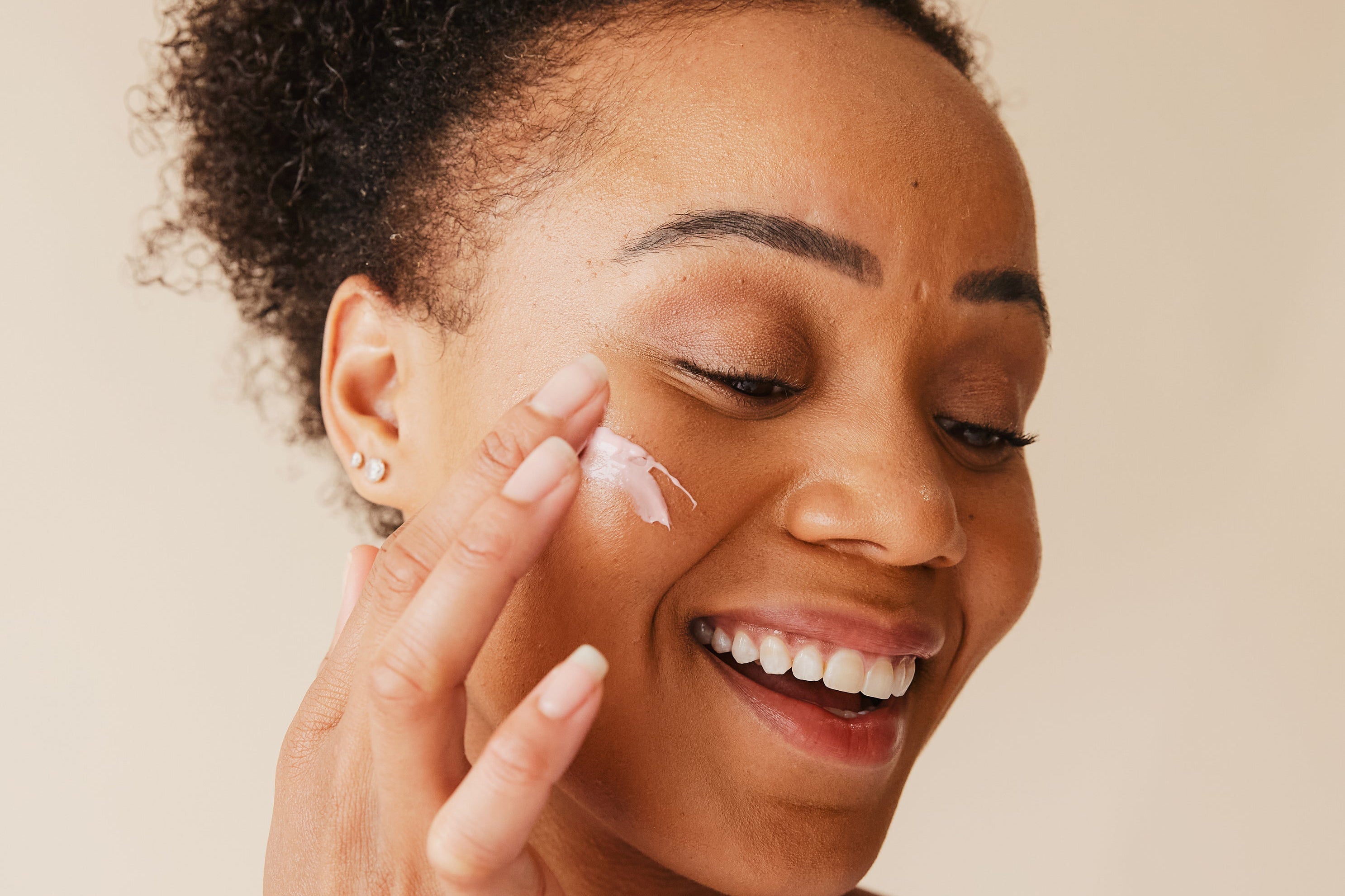 Frau trägt palmölfreie Naturkosmetik gegen Falten auf das Gesicht auf. Pflanzliches Gesichtcreme zur natürlichen Faltenreduktion“