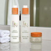 Esprit Naturel Naturkosmetik-Set mit Mizellenwasser, Reinigungsbalm und Tagescreme auf Marmor-Podest vor hellblauem Hintergrund – vegane, nachhaltige Hautpflege